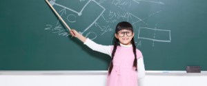 Humorous little girl playing teacher in classroom